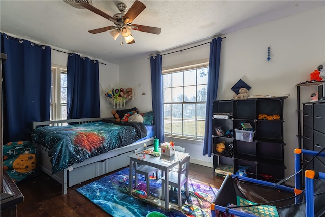 bedroom with ceiling fan, dark wood-type flooring, and a textured ceiling