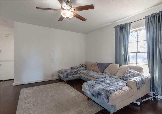 living room featuring ceiling fan, a textured ceiling, and dark hardwood / wood-style flooring