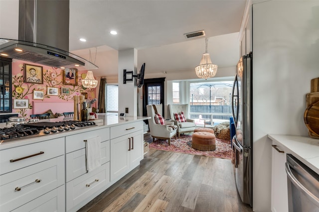 kitchen with white cabinetry, stainless steel appliances, island range hood, light hardwood / wood-style floors, and decorative light fixtures