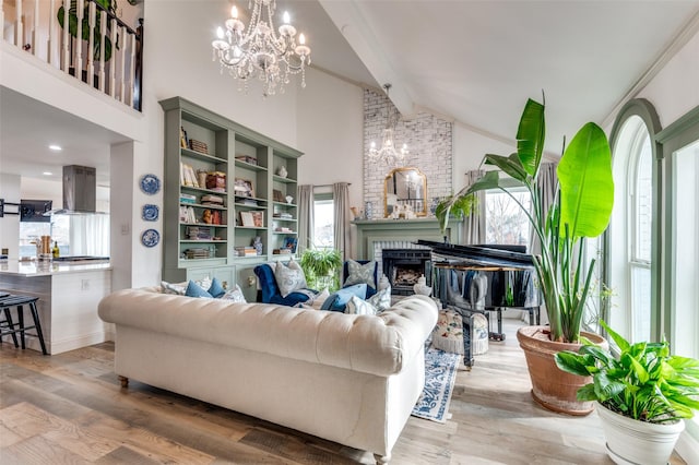 living room featuring high vaulted ceiling, a brick fireplace, light hardwood / wood-style flooring, a notable chandelier, and beamed ceiling