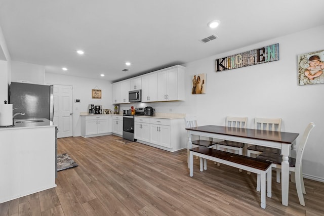 kitchen featuring appliances with stainless steel finishes, sink, white cabinets, and light hardwood / wood-style floors