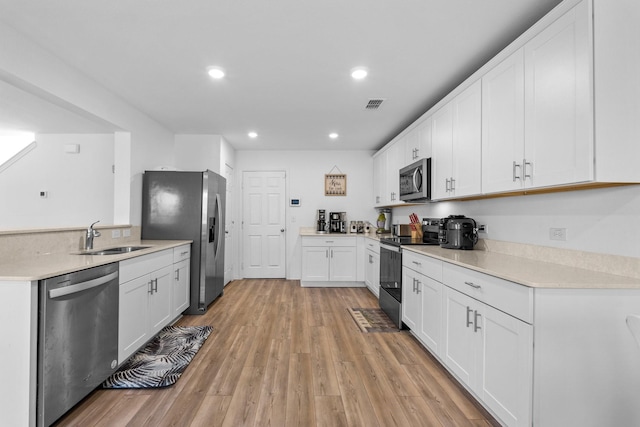 kitchen with white cabinetry, stainless steel appliances, light hardwood / wood-style floors, and sink