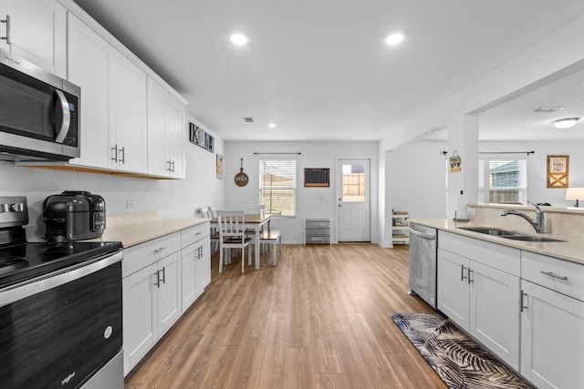 kitchen featuring sink, light hardwood / wood-style flooring, appliances with stainless steel finishes, a wealth of natural light, and white cabinets