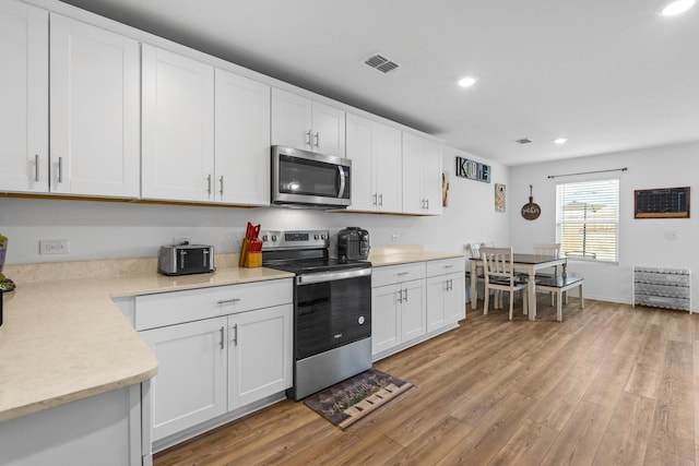 kitchen with white cabinetry, light wood-type flooring, and appliances with stainless steel finishes