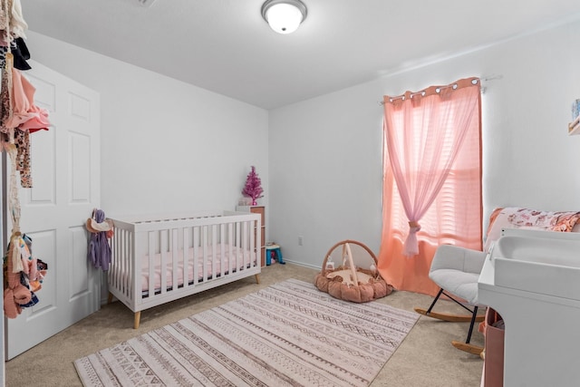 bedroom featuring light carpet and a crib