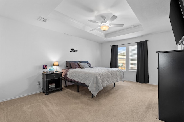 bedroom featuring crown molding, ceiling fan, a tray ceiling, and light carpet