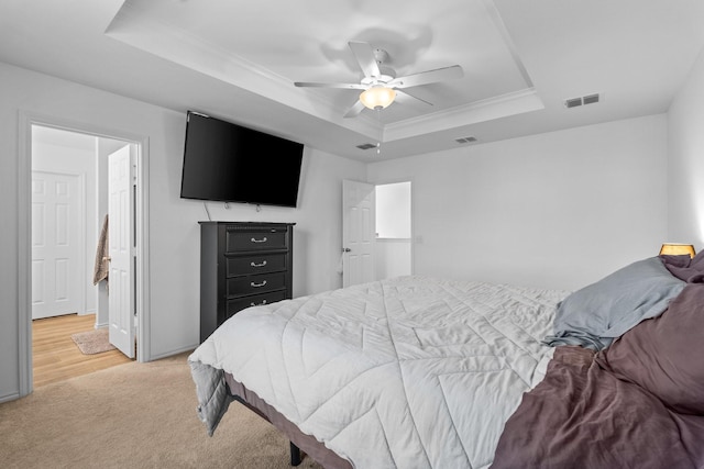 bedroom with a raised ceiling, crown molding, light carpet, and ceiling fan