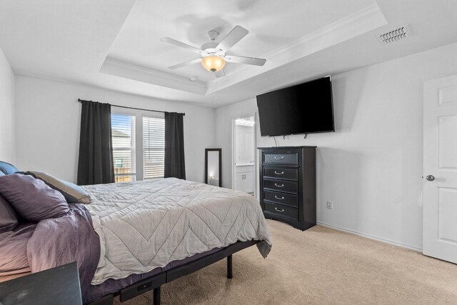 bedroom with ensuite bathroom, crown molding, ceiling fan, a tray ceiling, and light colored carpet