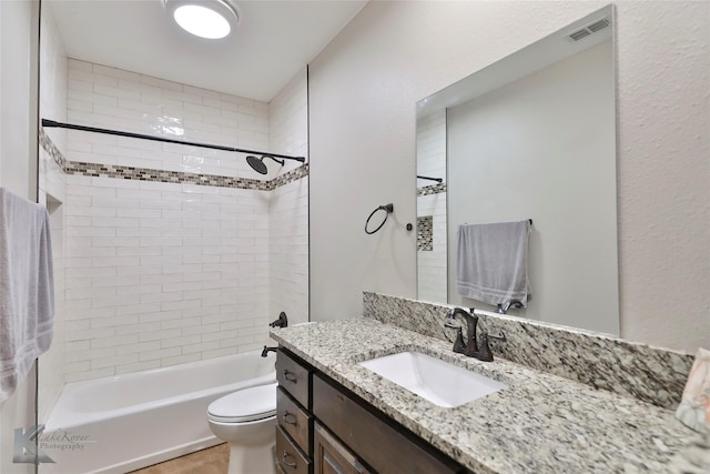 full bathroom featuring tiled shower / bath, vanity, and toilet