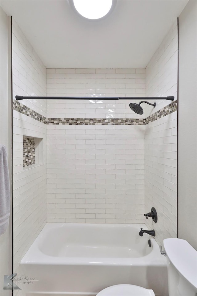 bathroom with tiled shower / bath and toilet