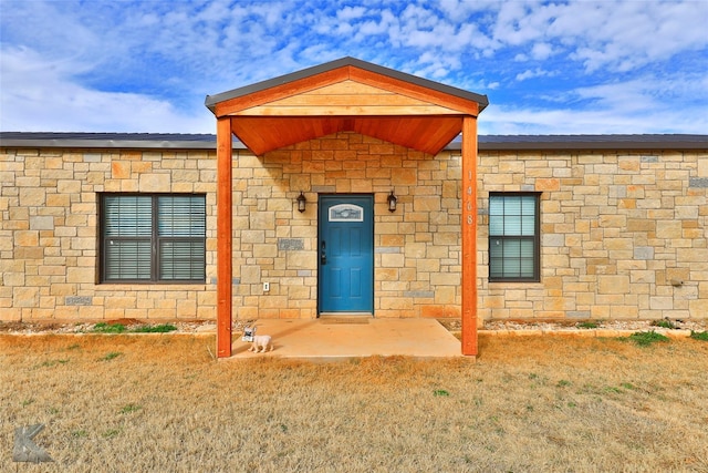 property entrance with a lawn