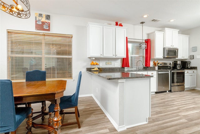 kitchen with appliances with stainless steel finishes, pendant lighting, and white cabinets