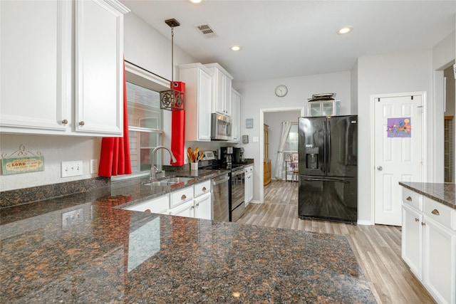 kitchen featuring pendant lighting, sink, appliances with stainless steel finishes, dark stone countertops, and white cabinets