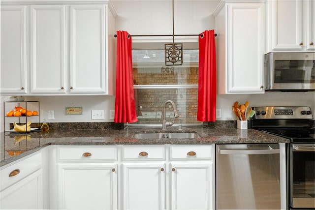 kitchen featuring appliances with stainless steel finishes, sink, dark stone counters, and white cabinets