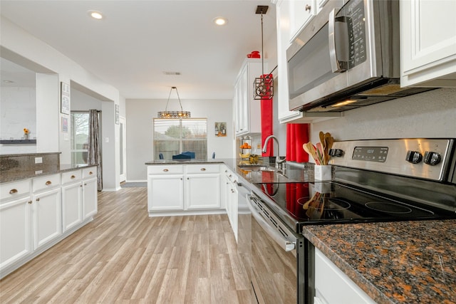 kitchen with stainless steel appliances, decorative light fixtures, kitchen peninsula, and white cabinets