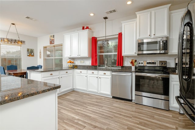 kitchen with sink, appliances with stainless steel finishes, white cabinetry, hanging light fixtures, and kitchen peninsula