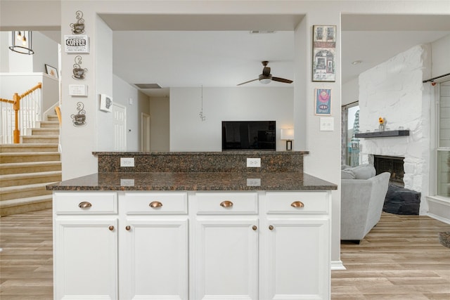 kitchen featuring white cabinetry, a fireplace, and dark stone countertops