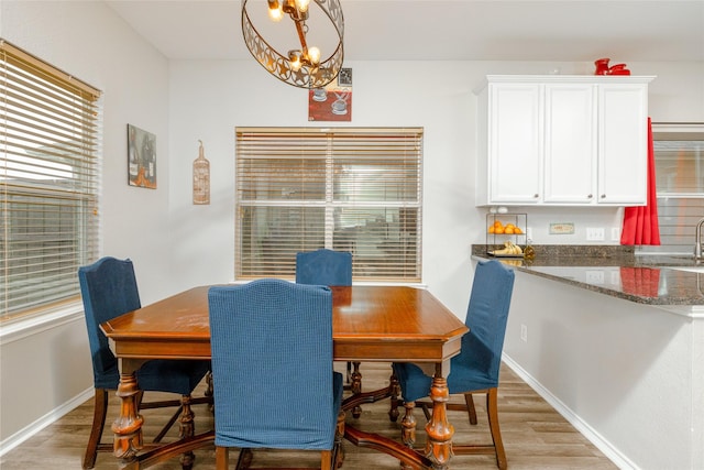 dining area featuring an inviting chandelier, sink, and light hardwood / wood-style floors