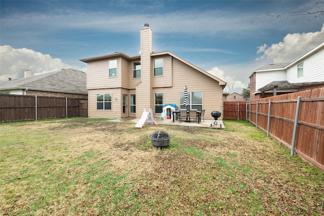 back of property featuring a yard, a patio area, and a fire pit