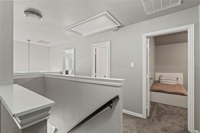 corridor with a textured ceiling and dark colored carpet