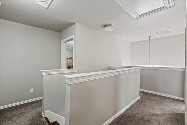 corridor featuring dark carpet and a textured ceiling