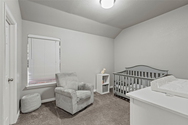 bedroom featuring a crib, vaulted ceiling, and carpet floors