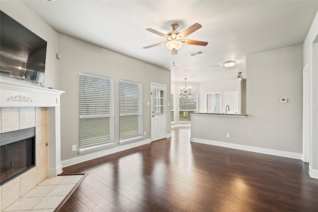 unfurnished living room featuring wood-type flooring, a fireplace, and ceiling fan with notable chandelier