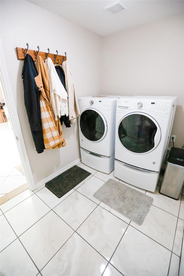 clothes washing area with washer and clothes dryer and light tile patterned floors