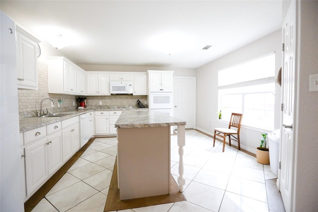 kitchen with white appliances, a kitchen island, and white cabinets