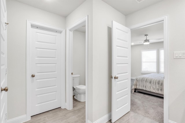 interior space with ceiling fan, hardwood / wood-style flooring, and toilet