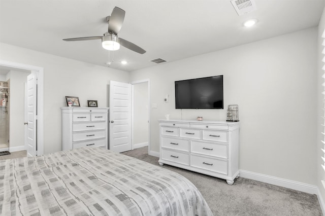 bedroom with ceiling fan, light colored carpet, and connected bathroom