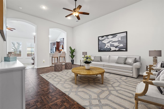 living room featuring recessed lighting, a ceiling fan, arched walkways, and baseboards