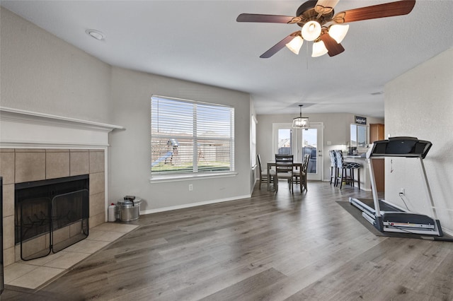 workout room with ceiling fan, a fireplace, and light wood-type flooring