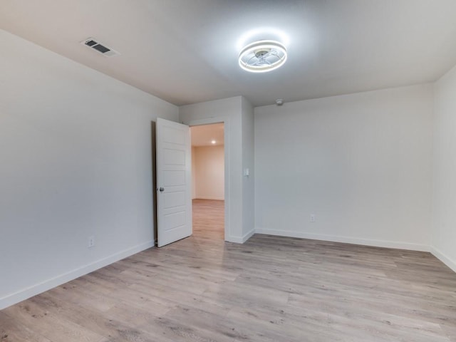 empty room with baseboards, visible vents, and light wood finished floors