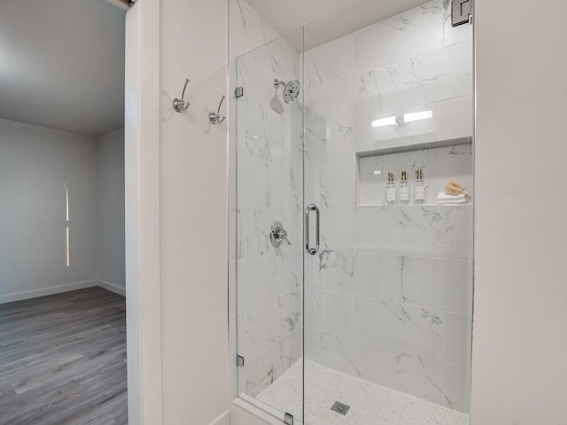 bathroom featuring a stall shower, baseboards, and wood finished floors