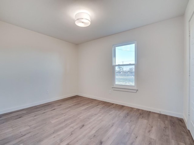 spare room featuring light wood-style floors and baseboards