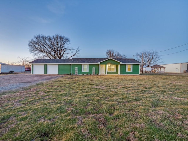 ranch-style home with a front yard and gravel driveway