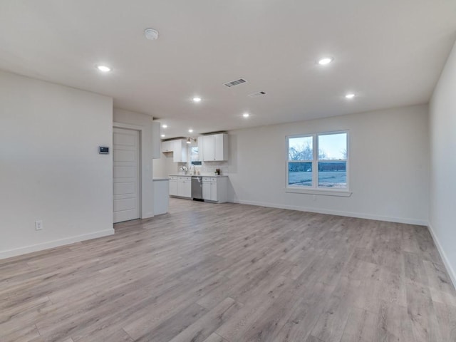 unfurnished living room with light wood-type flooring, baseboards, visible vents, and recessed lighting