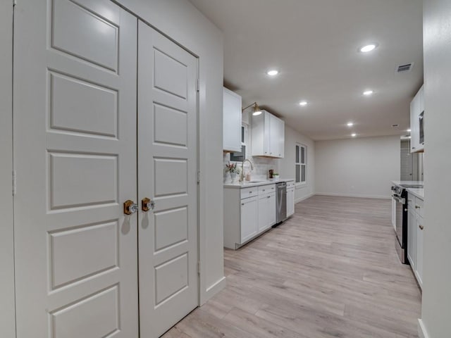 kitchen featuring appliances with stainless steel finishes, light wood-style floors, visible vents, and white cabinetry