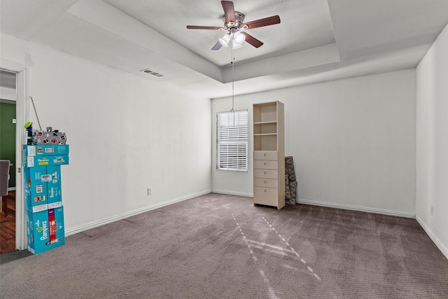 carpeted spare room with ceiling fan and a tray ceiling