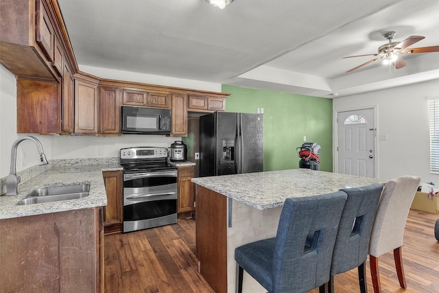 kitchen featuring a tray ceiling, sink, dark wood-type flooring, and black appliances