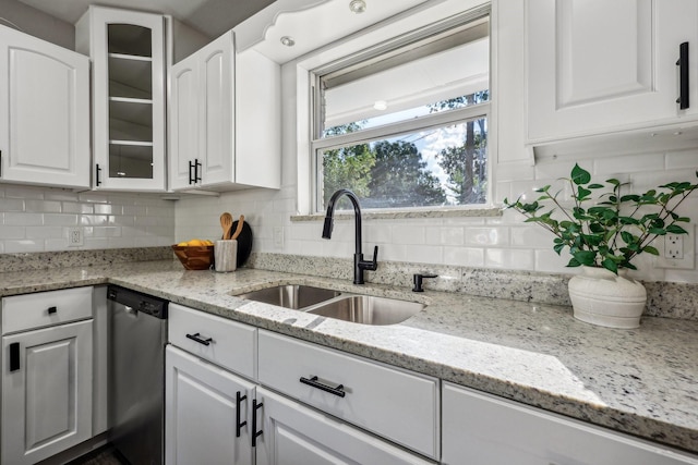 kitchen with decorative backsplash, stainless steel dishwasher, glass insert cabinets, white cabinets, and a sink