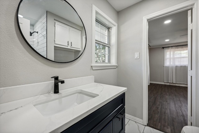 bathroom with a wealth of natural light, vanity, baseboards, and recessed lighting