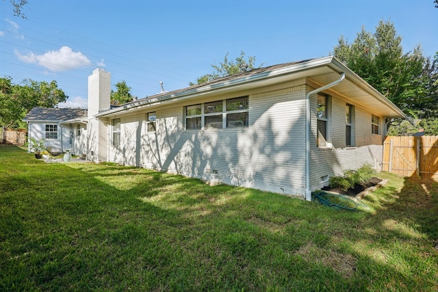 view of side of home featuring crawl space, brick siding, a yard, and fence