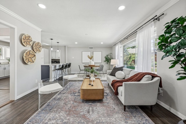 living area with ornamental molding, dark wood finished floors, visible vents, and baseboards