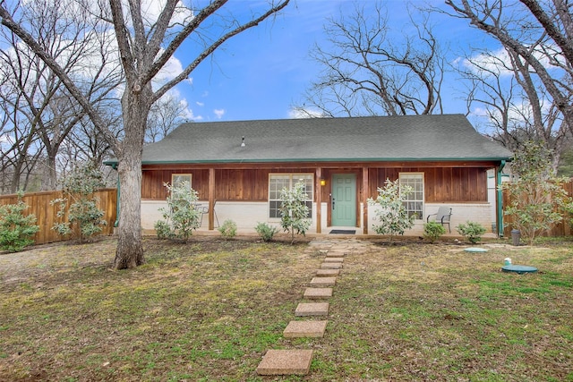 view of front of property featuring brick siding, fence, and a front lawn