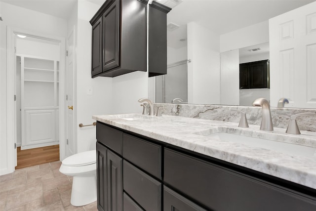 full bathroom with double vanity, stone finish floor, a sink, and toilet