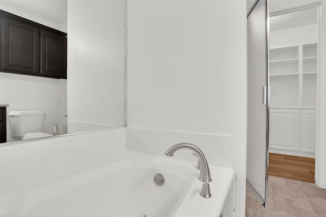 full bathroom featuring a whirlpool tub and toilet