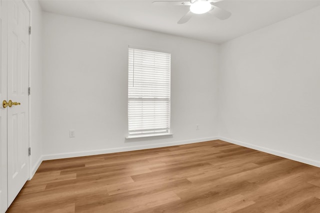 unfurnished room with light wood-type flooring, a ceiling fan, and baseboards