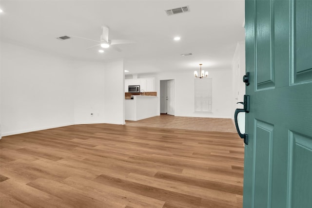 living room featuring ceiling fan with notable chandelier, ornamental molding, and light wood-type flooring